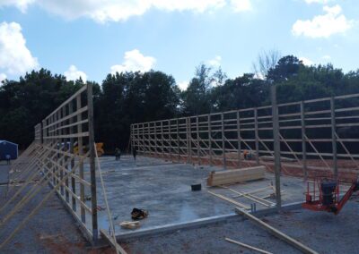 Wooden wall frames on a construction site with workers and blue sky.